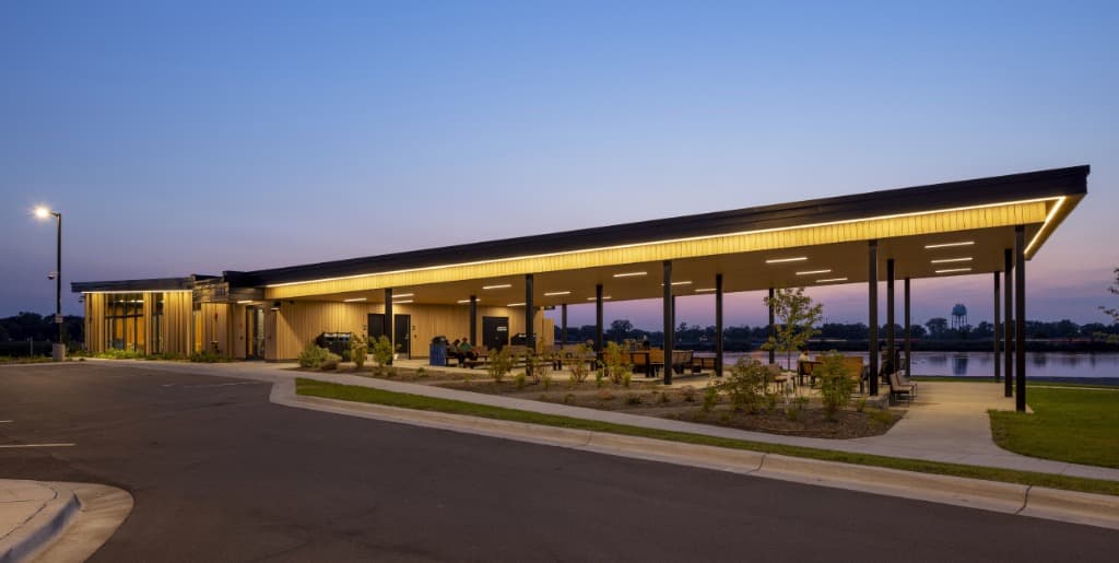 People fishing and relaxing at Moore Lake Park in Fridley with the city skyline in the distance.