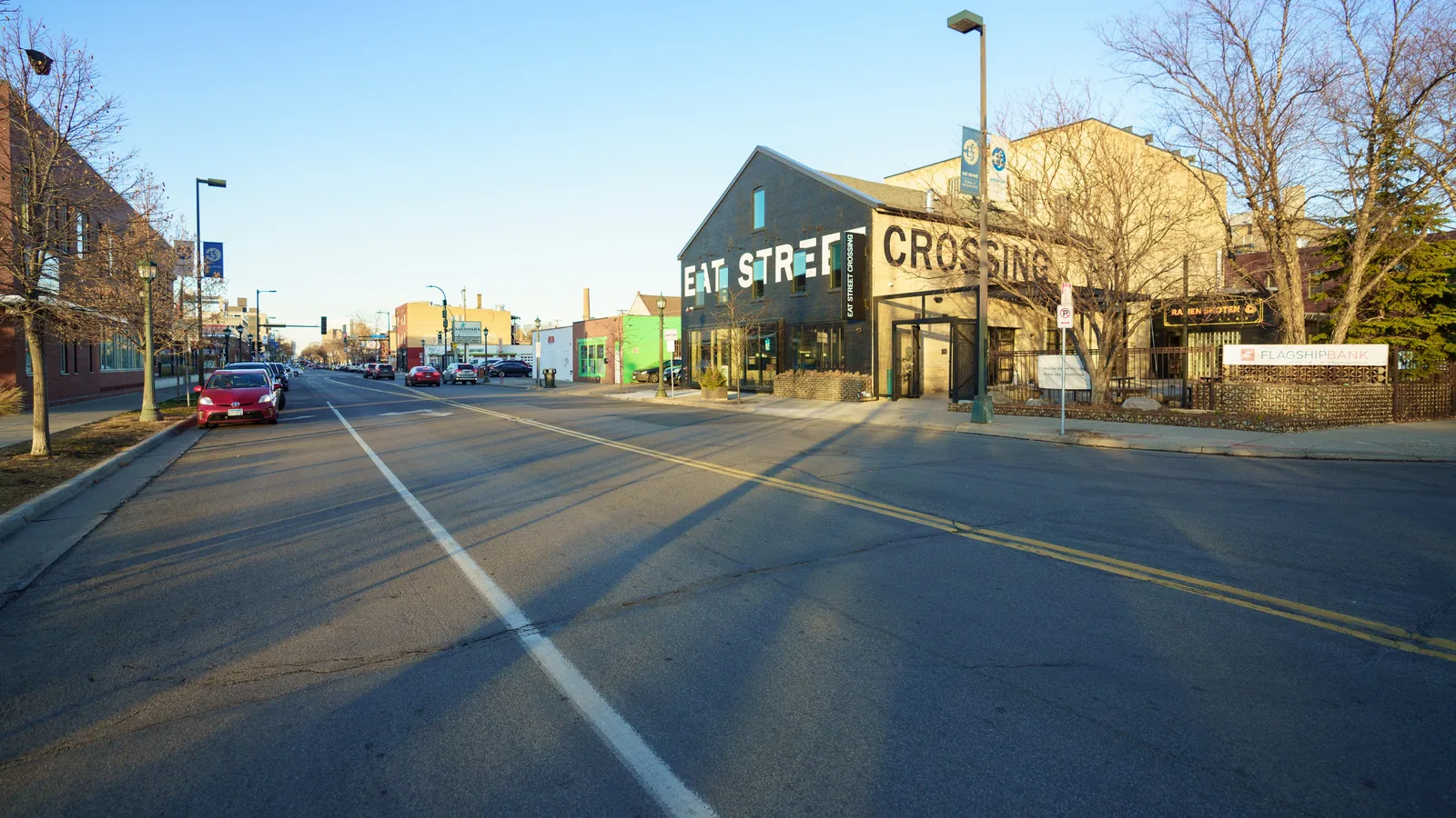 Nicollet Avenue on Eat Street in Whittier in late-afternoon sun, with the Eat Street Crossing food hall on the corner.