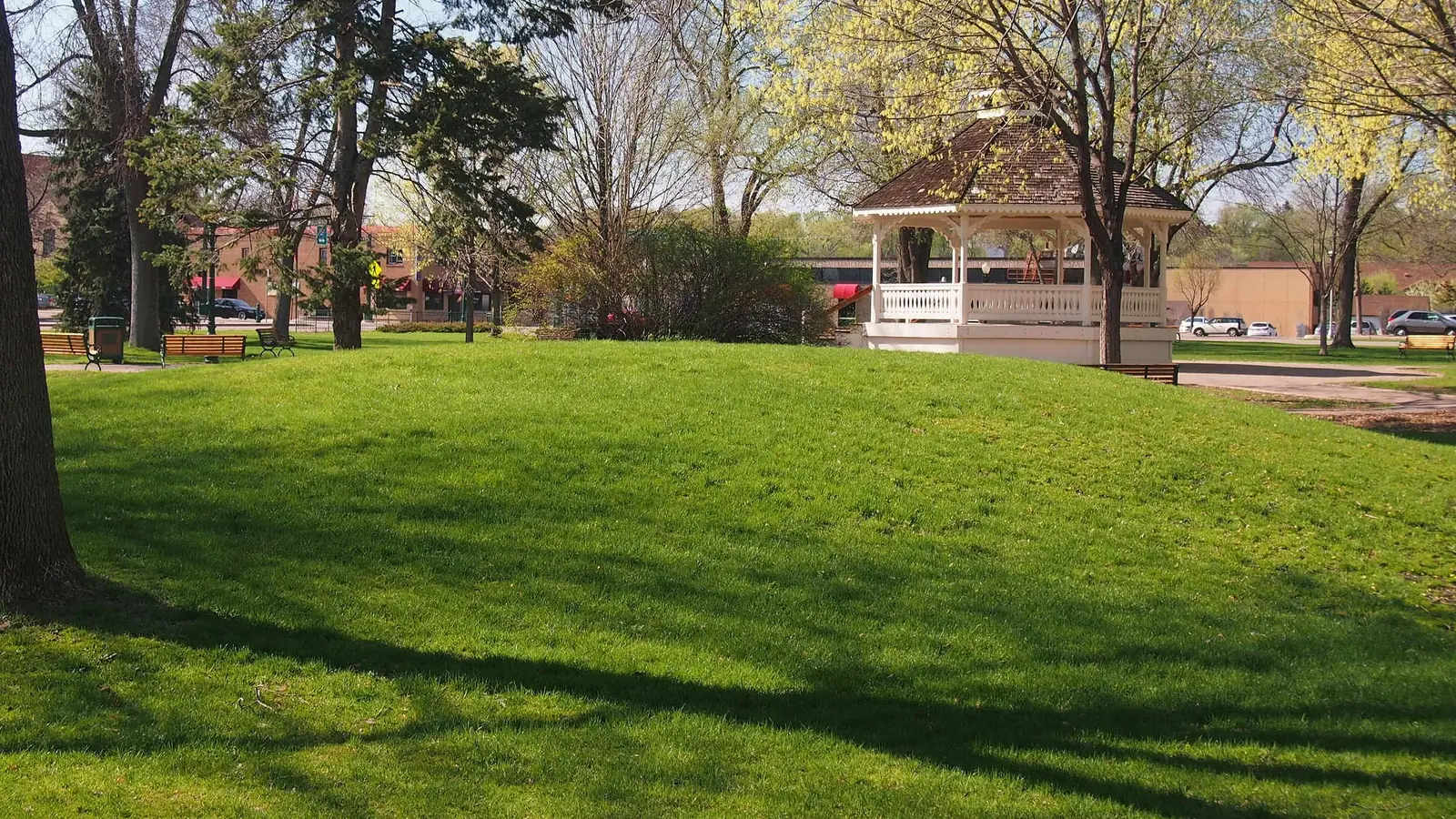 The white gazebo and lawn of the Public Square in downtown Chaska on a sunny spring day.